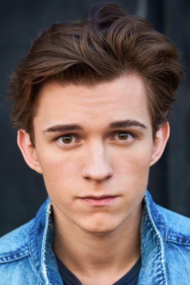 a close up of a person wearing a denim shirt and looking at the camera with a serious look on his face