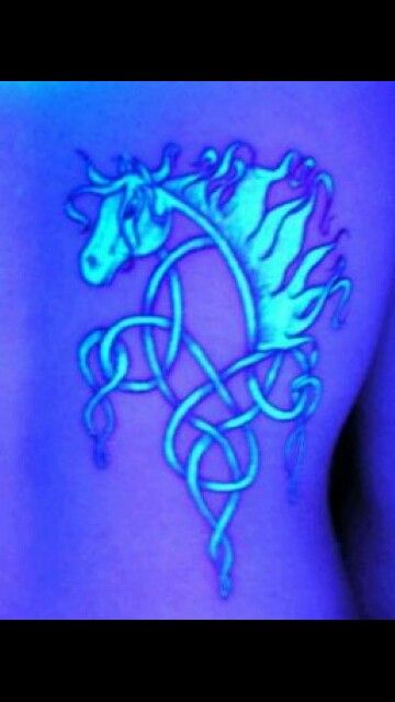 a woman's stomach with a glowing horse tattoo on her left side ribcage