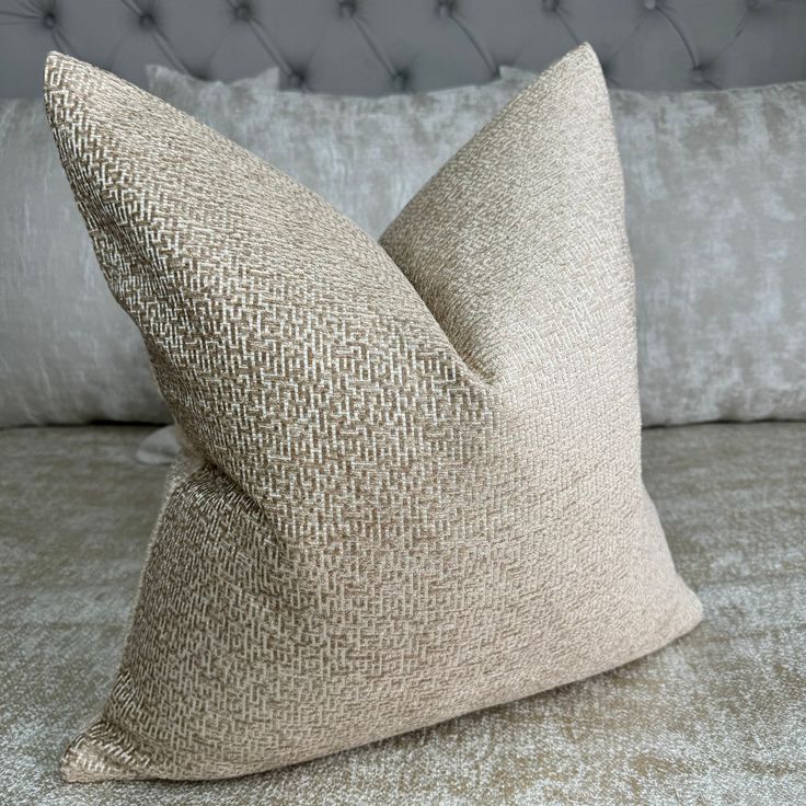 two pillows sitting on top of a bed next to each other