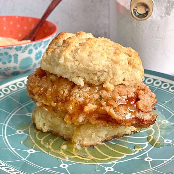 two biscuits stacked on top of each other on a blue and yellow plate next to a bowl of oatmeal