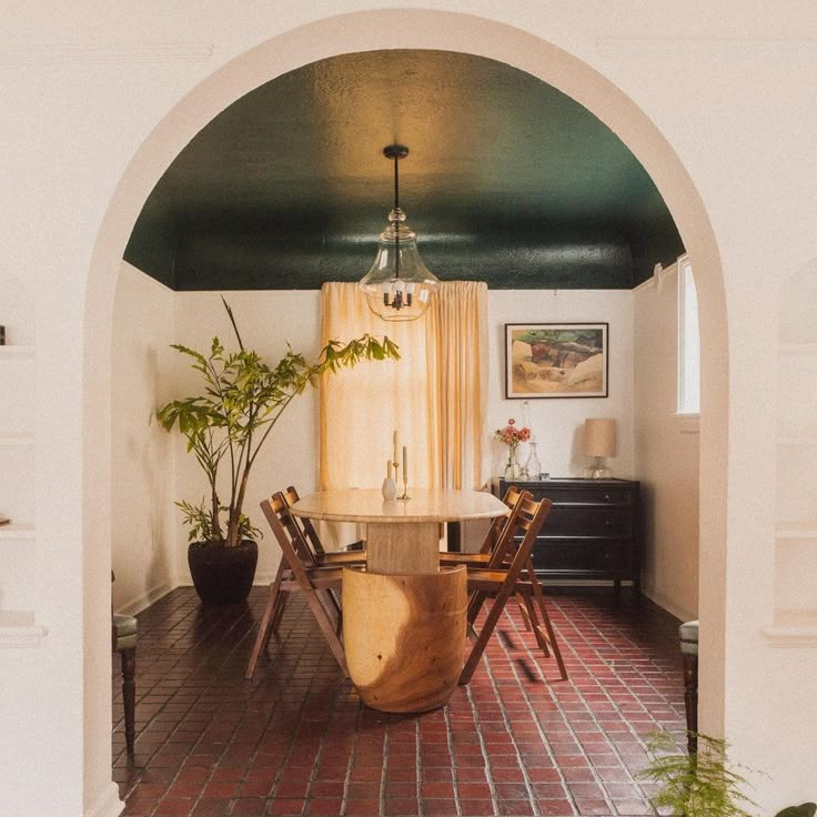 an archway leads into a dining room with a table, chairs and potted plants