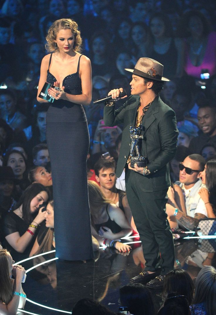 two people on stage one is holding an award and the other has a microphone in his hand