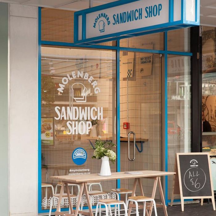 an outside view of a sandwich shop with tables and chairs in front of the window