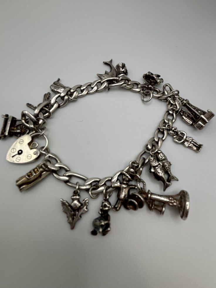 This beautiful vintage charm bracelet is made of sterling silver and contains 13 charms. The charms all reflect its mid-century character. Charms include a vintage phone, old fashioned car with moveable wheels, a baby with a crystal bead pacifier, and more. Bracelet is 7.75 inches in length and is closed with a heart lock charm connector. A truly special vintage piece.  As with all vintage Sterling silver, there can be some tarnishing. Many people enjoy this character and so I do not polish it--although it can be polished if you prefer. There is a bail attached without a charm but the 13 charms fill out the bracelet beautifully. Silver Vintage Charm Classic Jewelry, Vintage Antique Silver Sterling Bracelet, Vintage Nickel-free Sterling Silver Bracelet, Nickel-free Antique Silver Vintage Sterling Silver Bracelet, Collectible Classic Jewelry With Vintage Charm, Vintage Nickel-free Sterling Silver Bracelet In Antique Silver, Nickel Free Vintage Sterling Silver Bracelet, Nickel-free Vintage Sterling Silver Bracelet, Vintage Sterling Silver Bracelet In Antique Silver