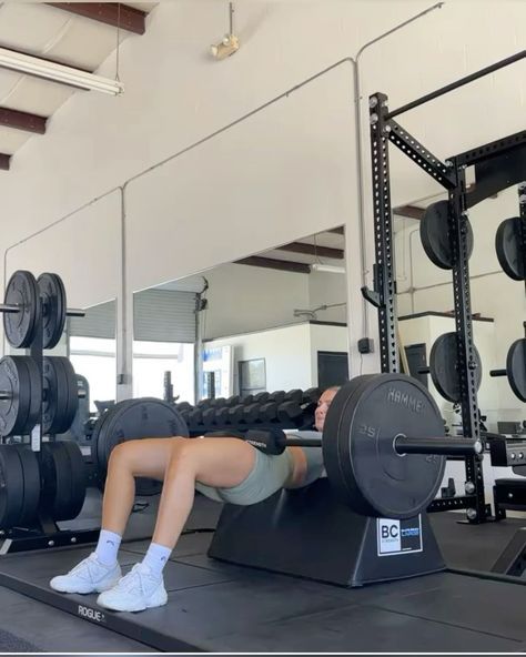 a woman is doing squats on a bench in a gym with barbells