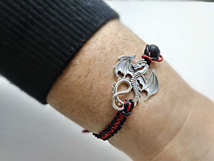 Dragon charm bracelet/ Essential oil bracelet/ fantasy bracelet/ Dragon Diffuser bracelet/ Aroma theraphy bracelet/ Macrame bracelet/ Animal charm bracelet/ Dragon lava bracelet/ Dragon adjustable bracelet/ friendship bracelet/ red and black dragon bracelet. This listing is for one (1) bracelet only This bracelet is nicely placed in a gift bags size (9x7cm).. This fantasy bracelet was made Chinese wax cord 1mm, with a Natural black lava stone 8mm beads, the dragon measures 34.5mm long 27.5mm wid Handmade Symbolic Braided Bracelets As Gift, Handmade Leather Bracelet With Waxed Cord For Gifts, Handmade Silver Wristband As Gift, Waxed Cord Braided Bracelet As Gift, Handmade Spiritual Leather Bracelet For Gift, Adjustable Braided Bracelet With Charms For Gift, Handmade Silver Leather Bracelet As Gift, Handmade Spiritual Leather Bracelet As Gift, Handmade Silver Leather Bracelet For Gift