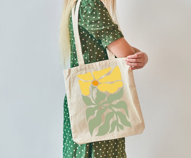 Celebrate your love for nature with our Boho Yello Daisy Flower Canvas Tote. This charming tote features a beautiful daisy design, perfect for those who embrace the boho aesthetic. Ideal for gardeners and plant lovers, this wildflower tote adds a touch of retro floral charm to any ensemble. Made from high-quality, durable canvas, it's designed to carry all your essentials with ease. Whether you're heading to the farmer's market, a picnic, or a day out, this trendy and stylish tote is the perfect Eco-friendly Yellow Bags For Spring, Everyday Green Shoulder Bag With Floral Print, Everyday Green Floral Print Shoulder Bag, Yellow Floral Print Bag For Daily Use, Yellow Floral Print Bags For Daily Use, Yellow Floral Print Everyday Bag, Yellow Flower-shaped Shoulder Bag For Daily Use, Everyday Yellow Floral Print Bags, Spring Yellow Canvas Bag For Everyday