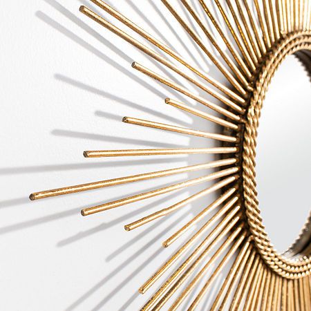 a gold sunburst mirror on the wall