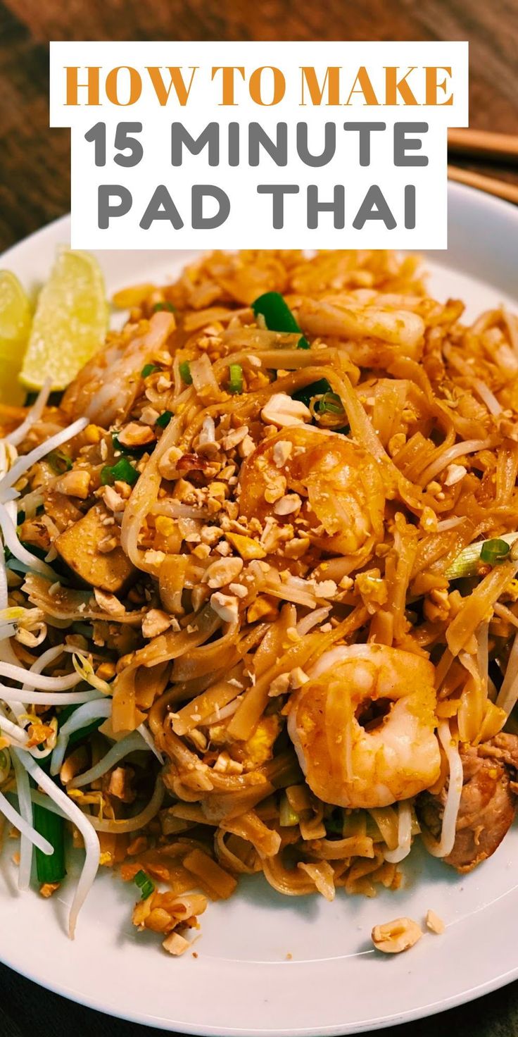 a white plate topped with pad thai noodles next to chopsticks and lemon wedges