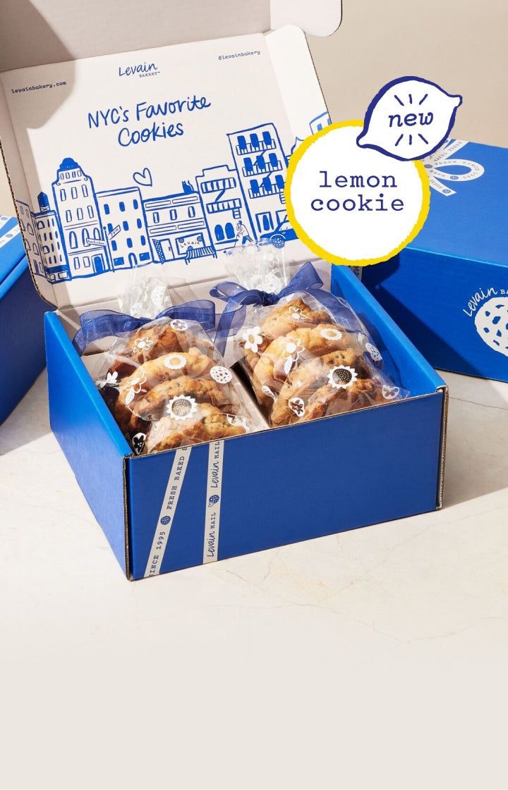 an open box of lemon cookies on a white table with a blue package behind it