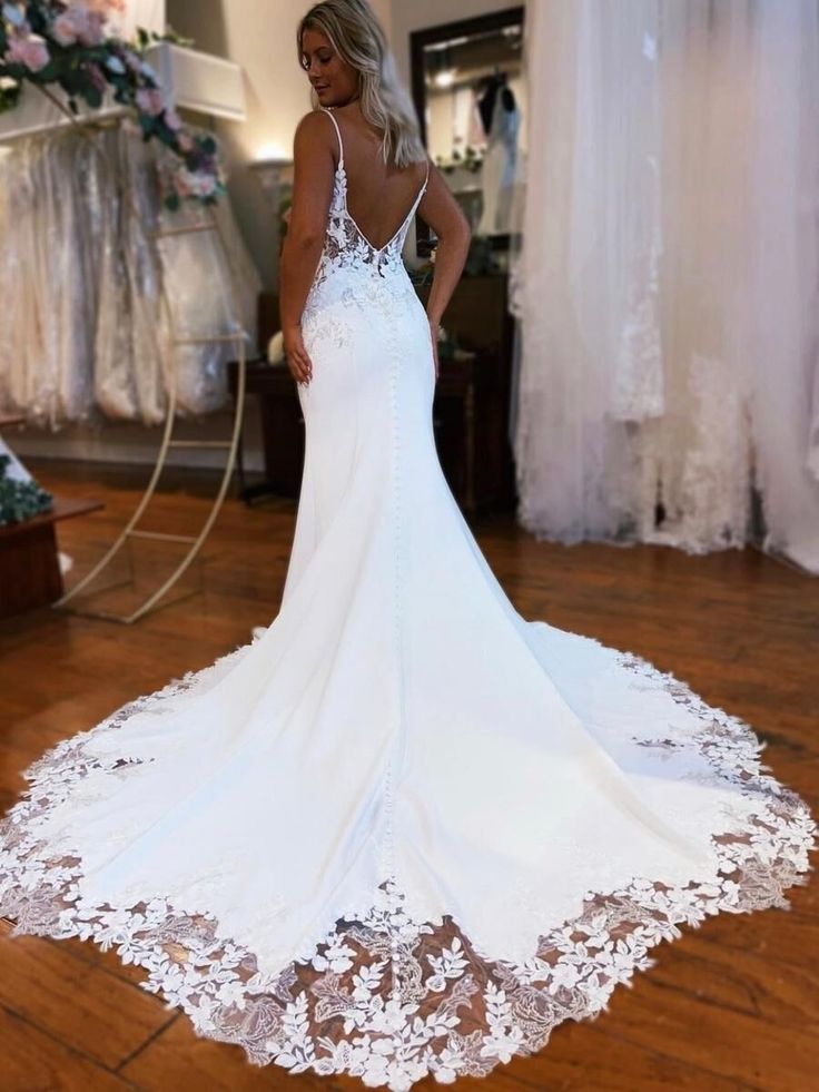 a woman in a white wedding dress looking down at the floor with her back to the camera