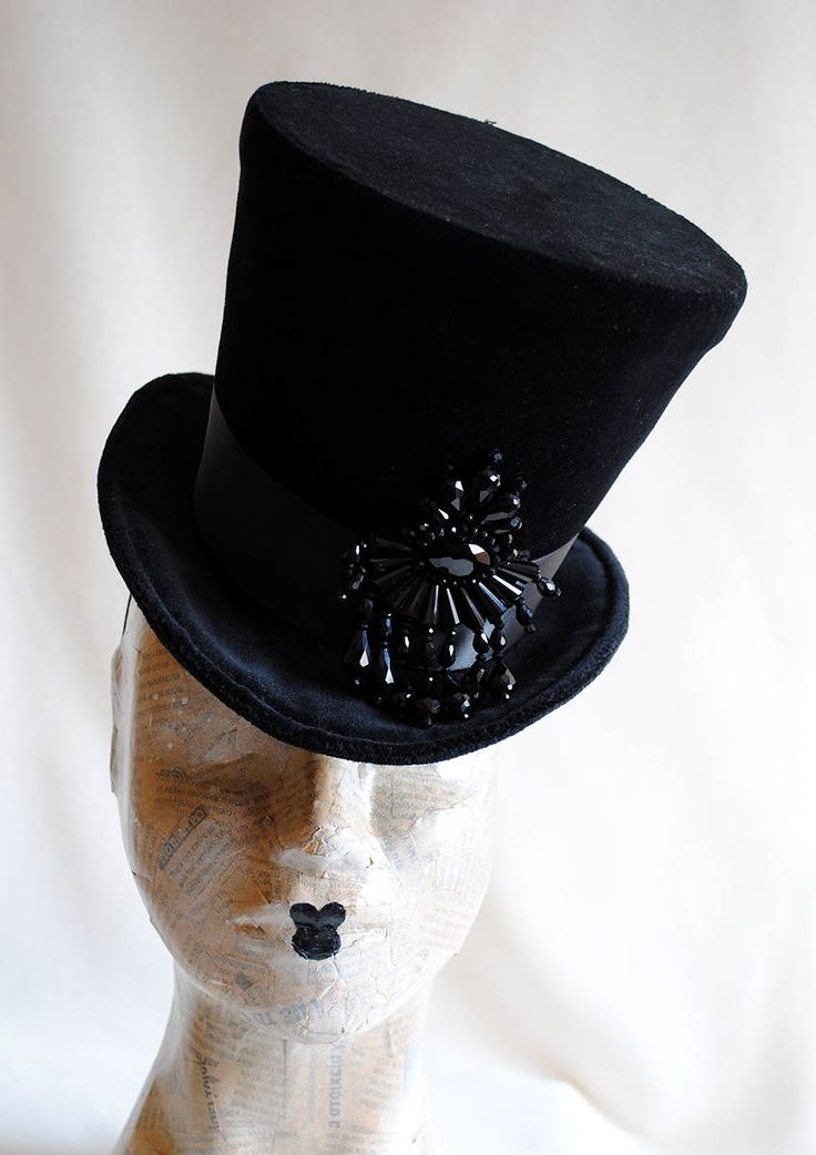 The Tease is a fabulous dark fashion lady's top hat,luxuriously elegant and feminine all the way! It is covered with rich black velvet and trimmed with black ribbon around the crown that ends in a beautiful double black bow at the back. The focal point is a majestic hand-beaded black crystal element at the side front that sparkles as you move around. Measurements : height 6.5 inches( 16 cm ) front to back 9 inches ( 23 cm ) side to side 8 inches ( 20 cm ) THIS IS NOT A FIT TO HEAD HAT NOT SUITAB Gothic Winter Costume Hats And Headpieces, Witchy Winter Party Costume Hats And Headpieces, Vintage High Crown Top Hat For Costume Party, Fitted High Crown Costume Hats And Headpieces, Fitted Costume Hat With Tall Crown, Fitted Tall Crown Costume Hats, Vintage Top Hat For Costume Party, Gothic Fitted High Crown Costume Accessories, Fitted Witchy Party Hat