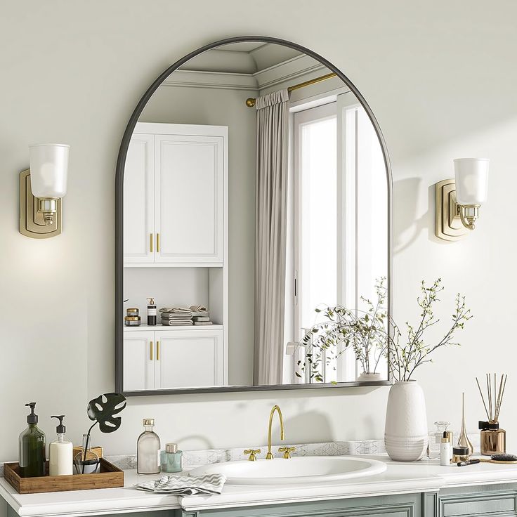 a bathroom with a large oval mirror above the sink, and gold faucet