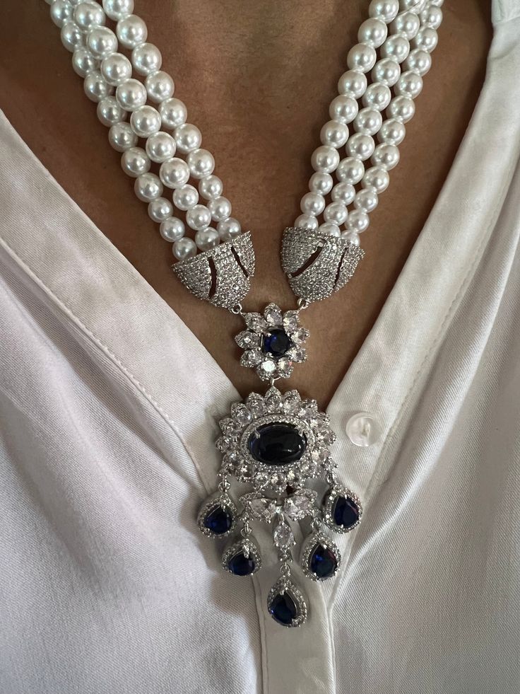 Discover the epitome of elegance with our premium necklace set. Crafted with precision and designed to turn heads, this set is a true masterpiece. Product Details: Material: Each piece is meticulously handcrafted from high-quality brass, beads, CZ Stones, Fashion Pearls, Faux Diamond, Blue color stone in the center. Necklace Dimensions: Weight: 115 grams Drop Length: 11 inches. Closure Type: Hook Adjustable Size: Yes Earring Dimensions (Per Pair): Weight: 40 grams. Length: 6.5 cm. Width: 3.5 cm. Opulent Round Necklaces For Formal Occasions, Opulent Formal Necklaces With 17 Jewels, Elegant Pendant Jewelry Sets, Exquisite Bridal Necklace With Cubic Zirconia Jewels, Elegant Formal Necklaces With Detachable Pendant, Elegant Formal Necklace With Detachable Pendant, Elegant Formal Jewelry Sets With Pearl Pendant, Elegant Formal Jewelry With Detachable Pendant, Elegant Pearl Pendant Jewelry Set For Formal Occasions