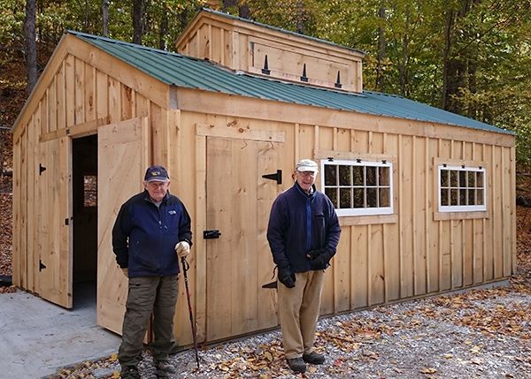 two men standing in front of a small cabin