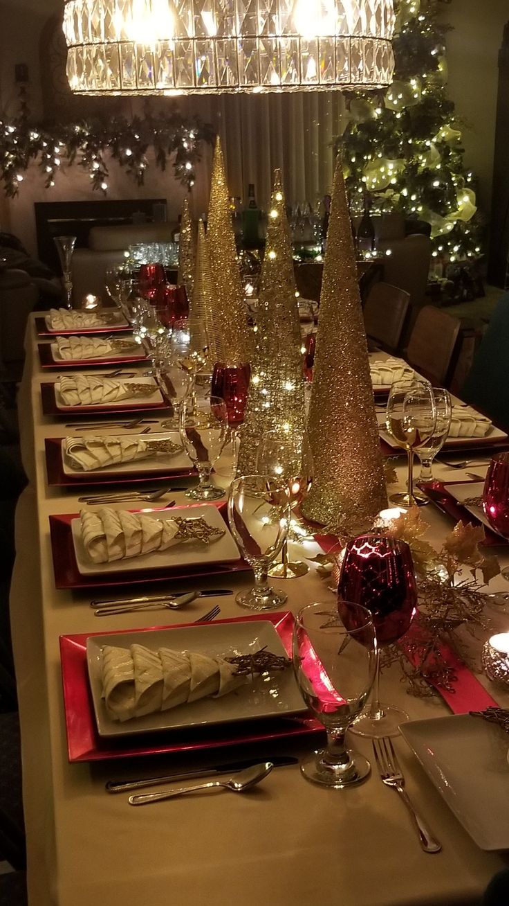 the table is set for christmas dinner with silverware and red napkins on it