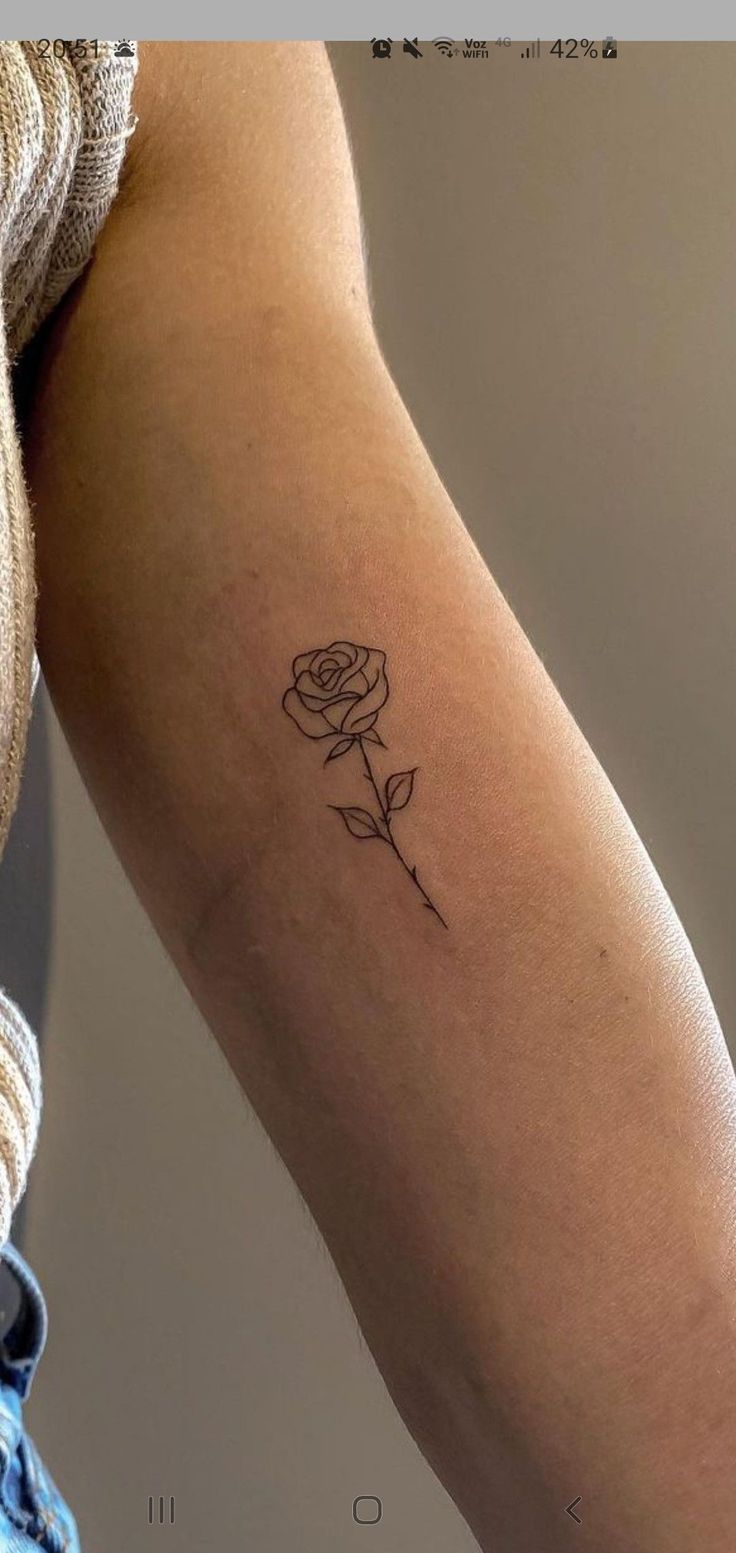 a woman's arm with a single rose tattoo on the left side of her arm