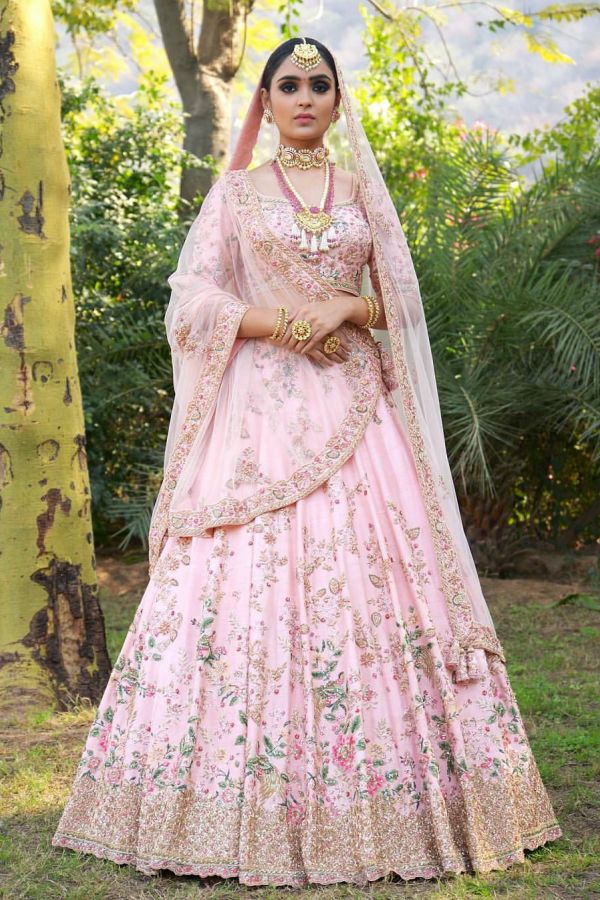 a woman wearing a pink lehenga with gold embroidery on the chest and sleeves