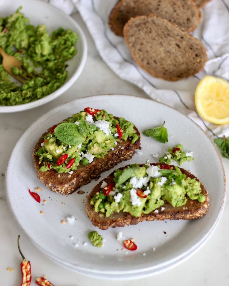 two pieces of bread with guacamole on top and some other food in the background