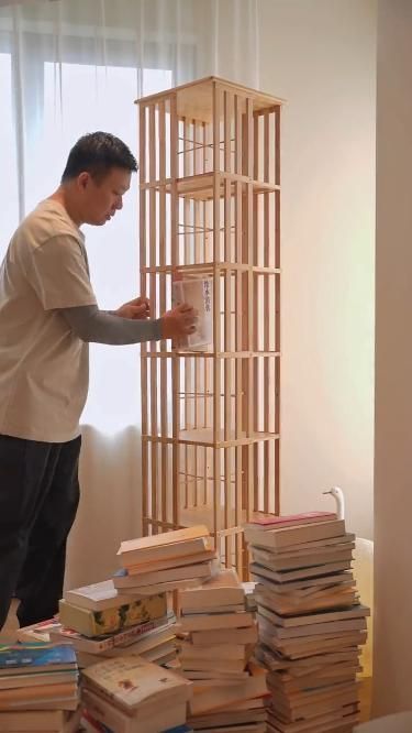 a man standing in front of a stack of books next to a tall bookcase