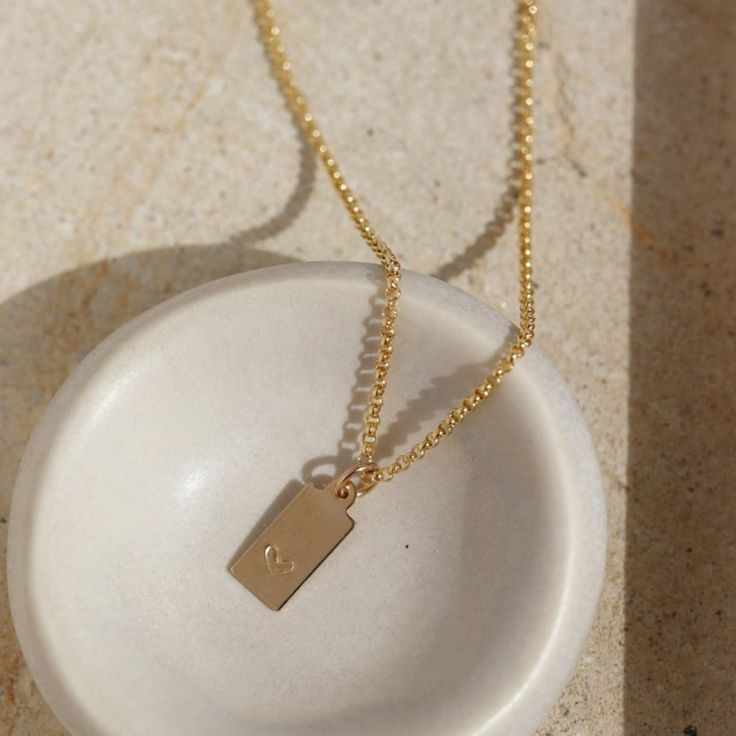 Our sweet Mini Tag Necklace hand stamped with a heart. This necklace makes a beautiful gift for anyone near and dear to your heart! DETAILS Offered in 14k gold fill or sterling silverLengths 14", 16" & 18" with a 1" chain extender clasp The tag measures 1/2" x 1/4" Dainty Everyday Necklace With Rectangular Pendant, Simple Everyday Pendant Charm Necklace, Dainty Everyday Heart Charm Necklace, Everyday Heart Necklace With Round Pendant, Minimalist Everyday Jewelry With Heart Charm, Minimalist Jewelry With Heart Charm Round Pendant, Everyday Initial Pendant Necklace With Heart Charm, Minimalist Heart Charm Jewelry For Everyday, Minimalist Jewelry With Heart Charm On Round Pendant