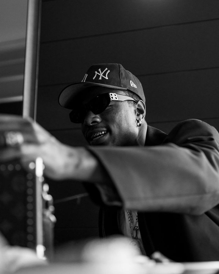 a black and white photo of a man in a baseball cap with his hand out