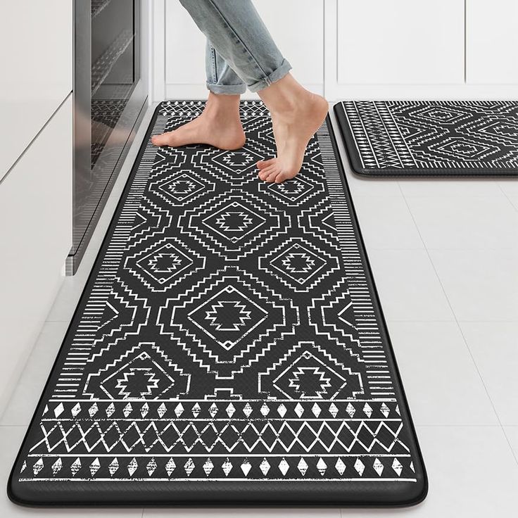 two black and white rugs on the floor in a kitchen with one person stepping up