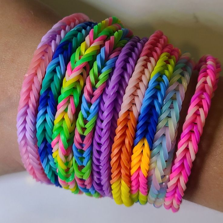 several different colored bracelets on someone's arm, each with an intricate braid design