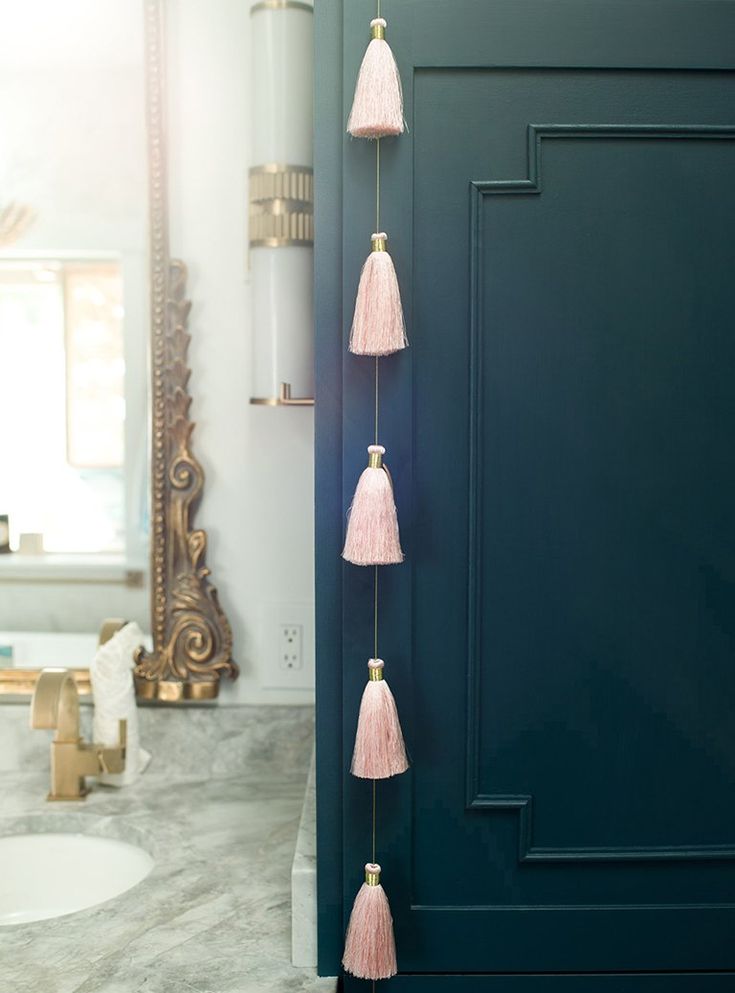 three pink tassels hanging from the side of a blue door in a bathroom