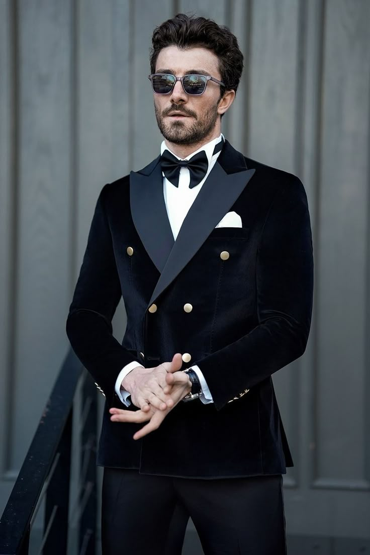 a man in a tuxedo and sunglasses poses for the camera with his hands on his hips