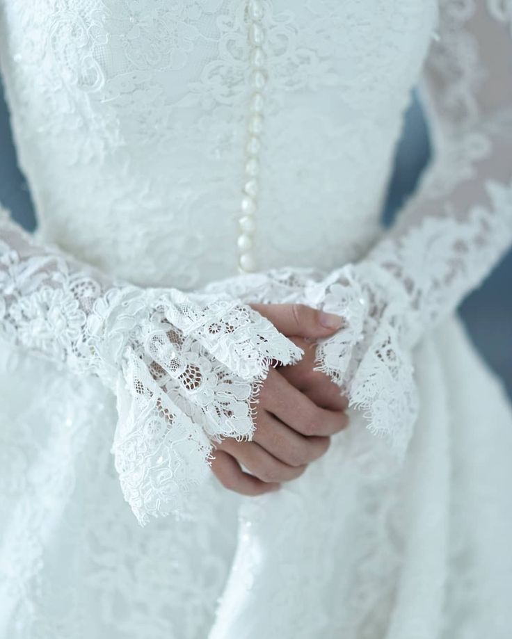 a close up of a person wearing a wedding dress and holding a white lace glove