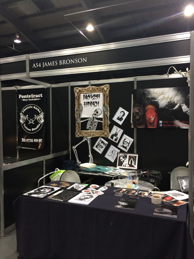 an exhibit booth with black tables and pictures on the wall, including framed art work