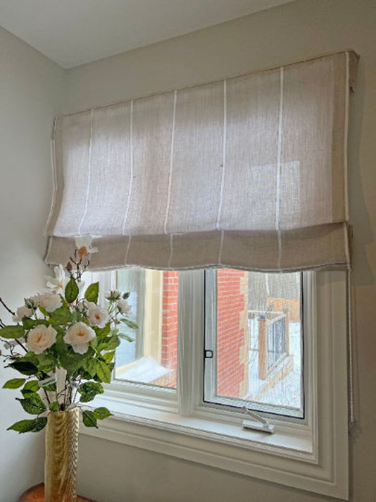 a vase filled with flowers sitting on top of a wooden table next to a window