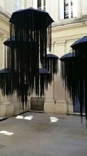 several black umbrellas hanging from the ceiling in an open area with concrete flooring