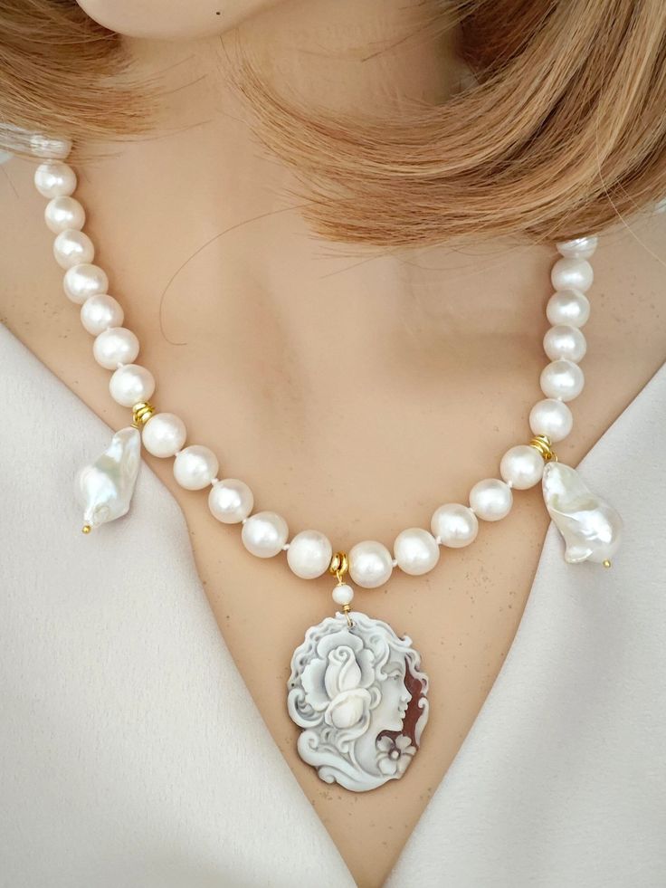 Necklace with hand-knotted 10 mm natural white pearls with authentic sardonic shell cameo hand-carved in Torre del Greco depicting a woman's head 4 x 3 cm in size and 2 natural white baroque pearls. Gold-plated 925 silver lobster clasp. Length 46 cm (18 inches). Mother Of Pearl Pendant Pearl Necklace, Elegant Cameo Pendant Necklace, Mother Of Pearl Round Bead Necklaces, Mother Of Pearl Necklace With Round Beads, White Cameo Necklace For Gift, Formal Mother Of Pearl Necklace, Elegant White Cameo Necklace, White Pearl Necklace, Italian Jewelry