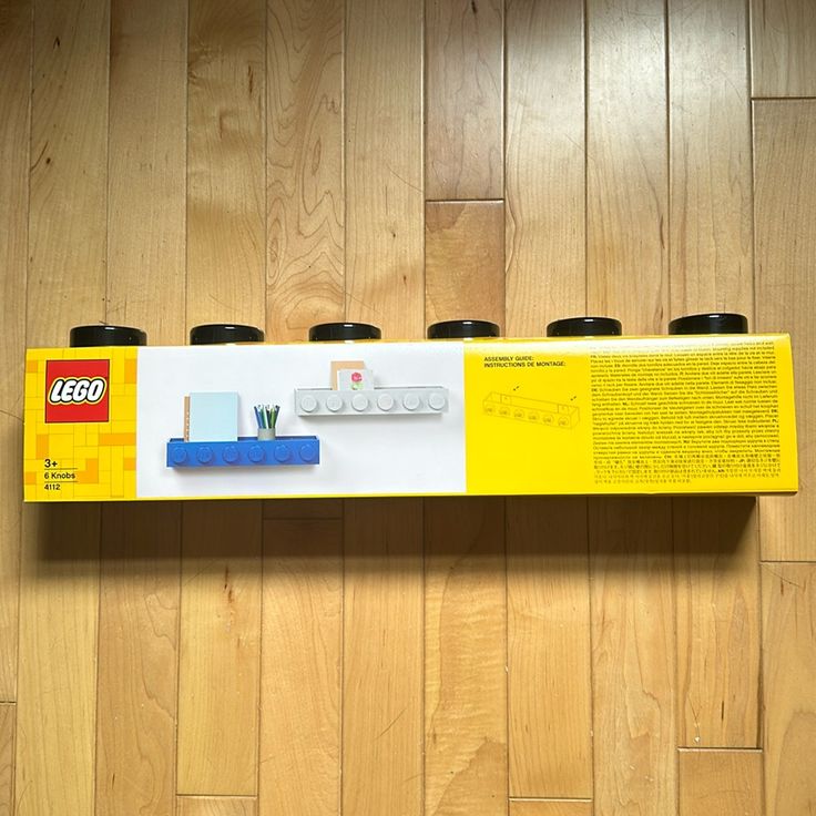 a lego box with four cups in it sitting on a wooden floor next to a wall