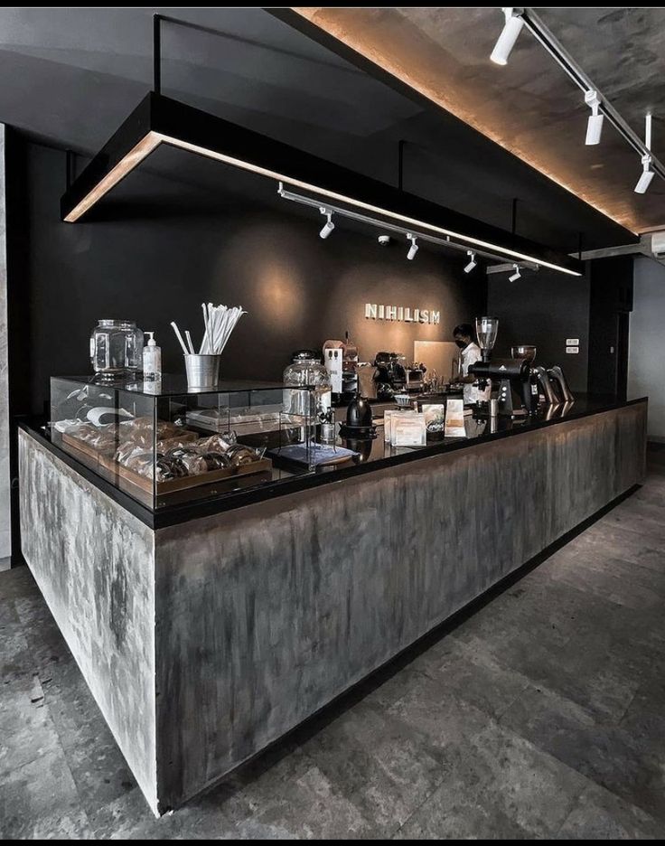 a counter with many items on it in a room that has black walls and concrete flooring