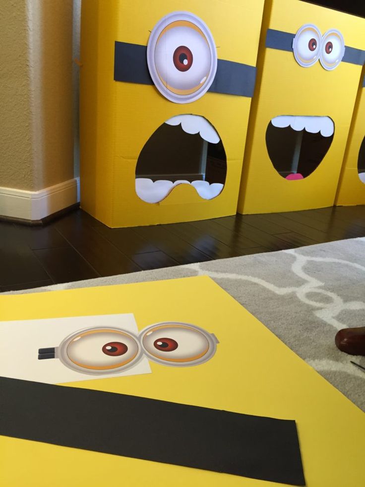 three cardboard boxes with faces and eyes on them sitting in front of a carpeted floor