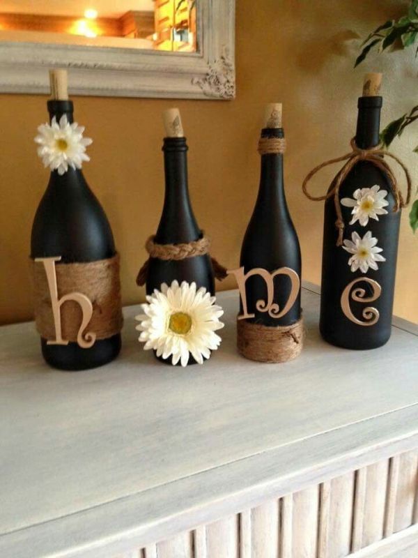 three wine bottles are decorated with daisies and burlocks to spell the word love