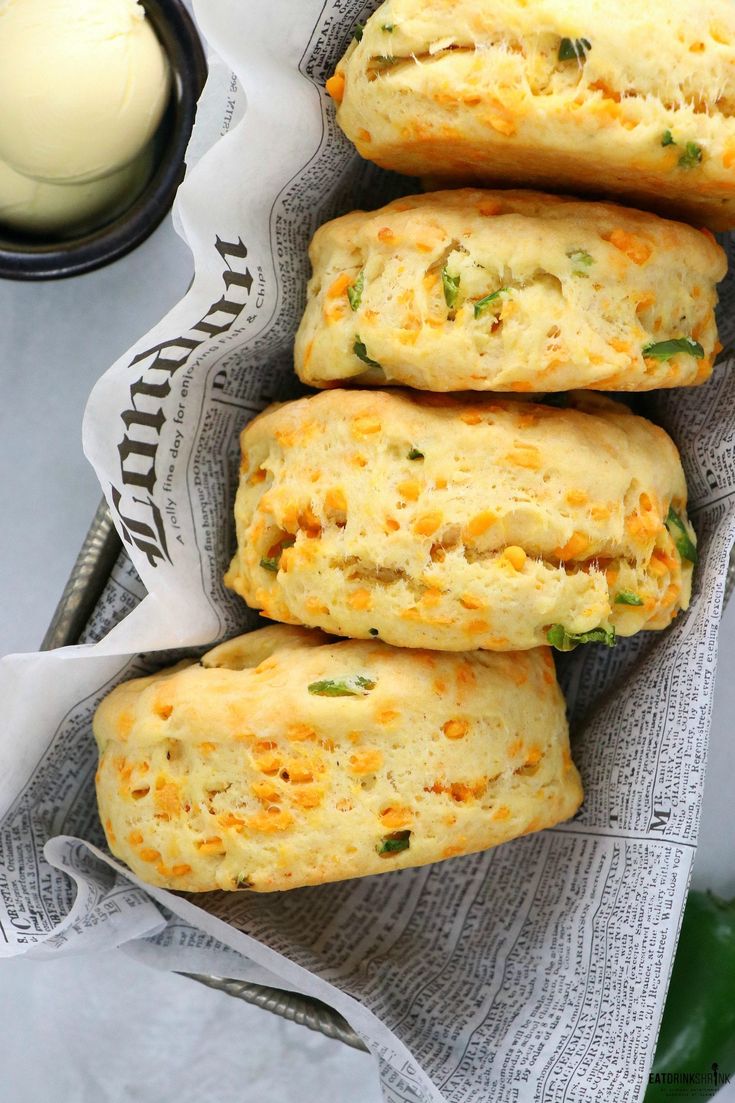 three cheesy biscuits sitting on top of a napkin next to a cup of cream