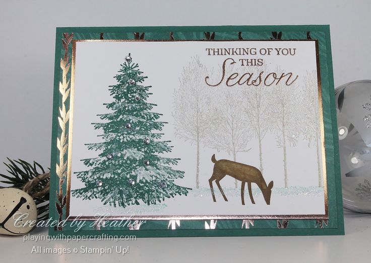 a christmas card with a deer and pine tree in the background, on a table