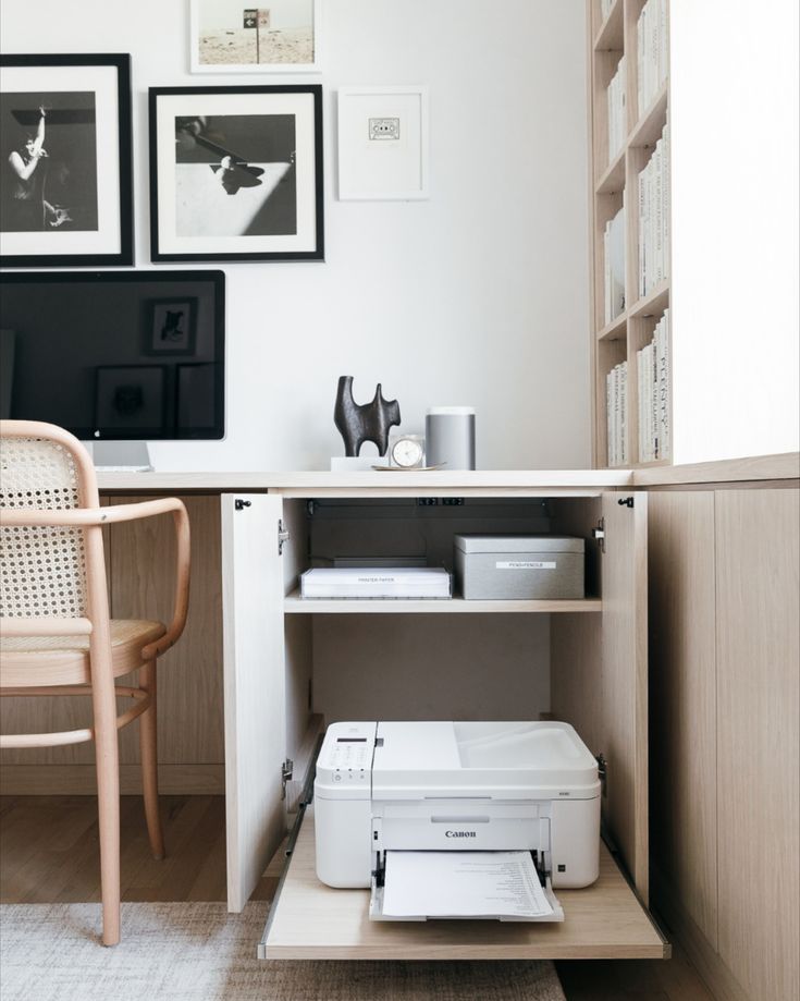 a white printer sitting on top of a wooden shelf next to a chair and desk