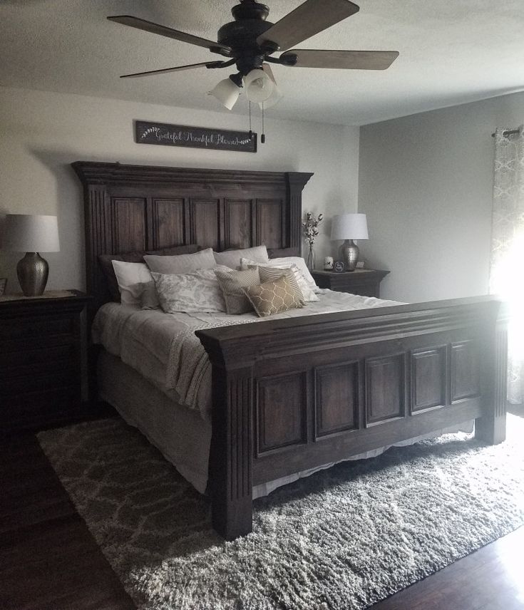 a bedroom with a bed, ceiling fan and two lamps on either side of the bed