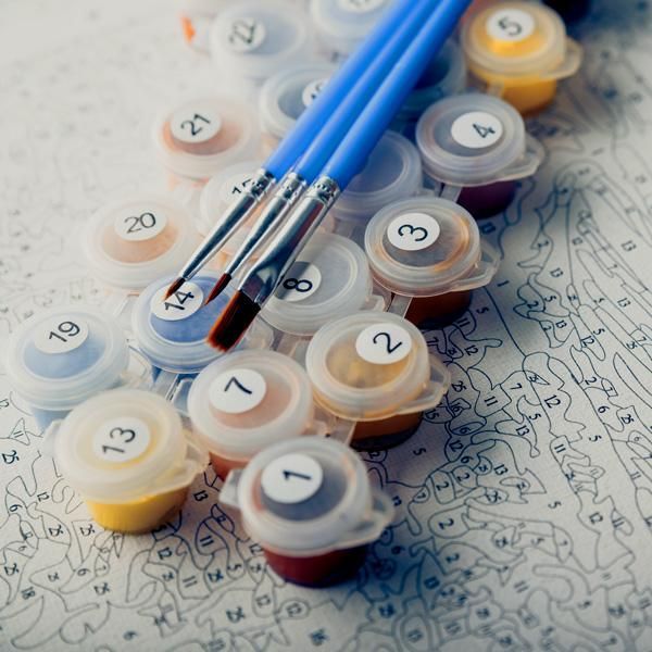 two paint brushes are sitting on top of some markers and ink bottles that have numbers painted on them