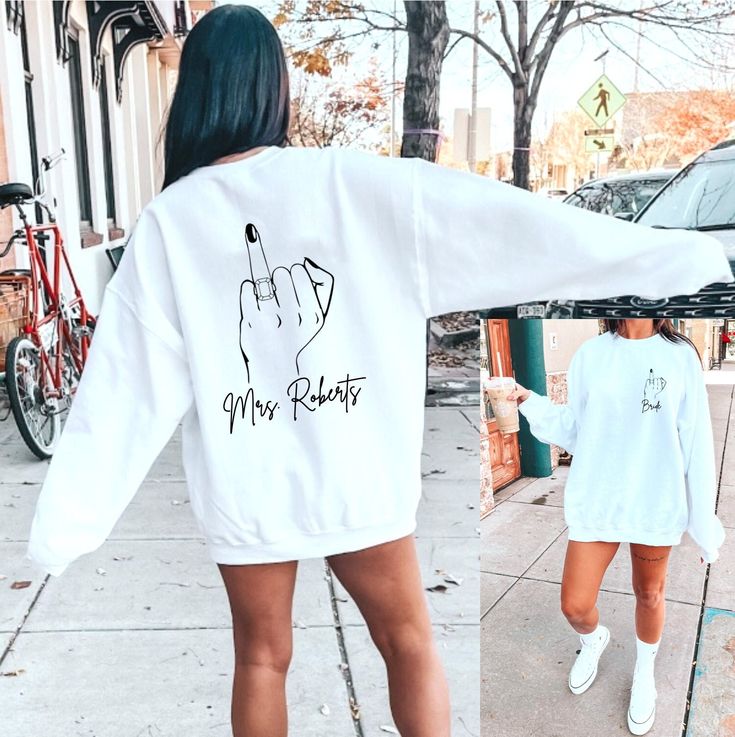 a woman walking down the street wearing a white sweatshirt and shorts with an image of a hand on it