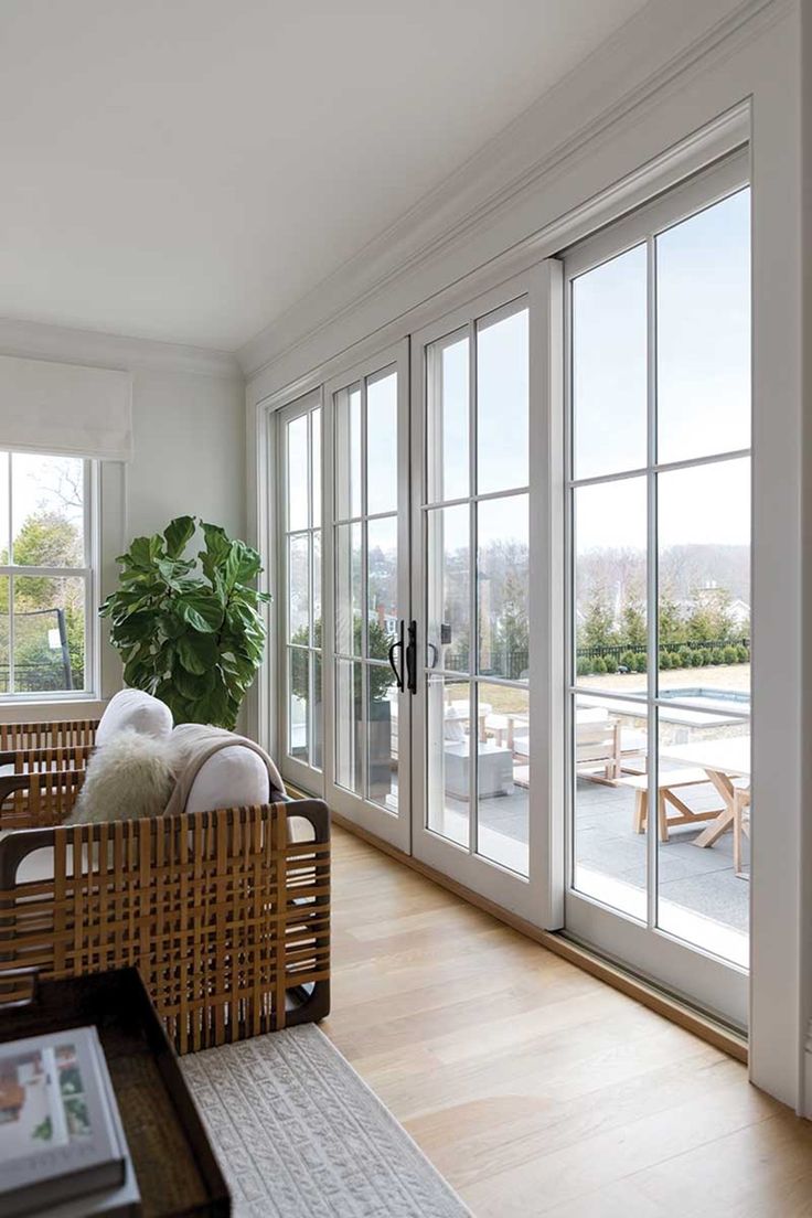 a living room filled with furniture and lots of glass doors leading to a patio area