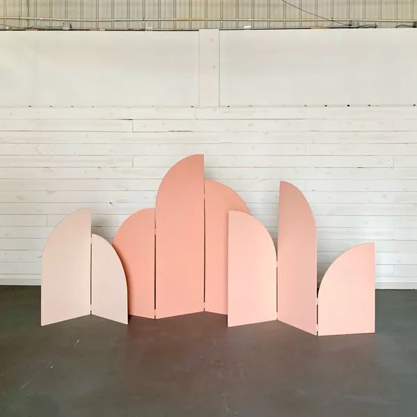 a pink sculpture sitting on top of a cement floor next to a white brick wall