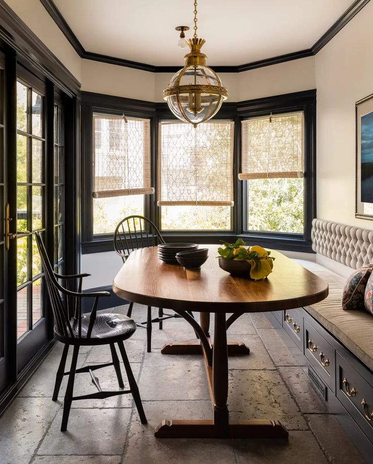 a dining room table with two chairs and a bowl of fruit on top of it