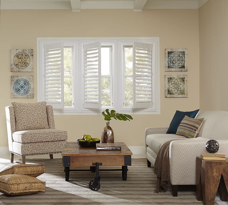 a living room filled with furniture and windows covered in white shuttered shades on the windows