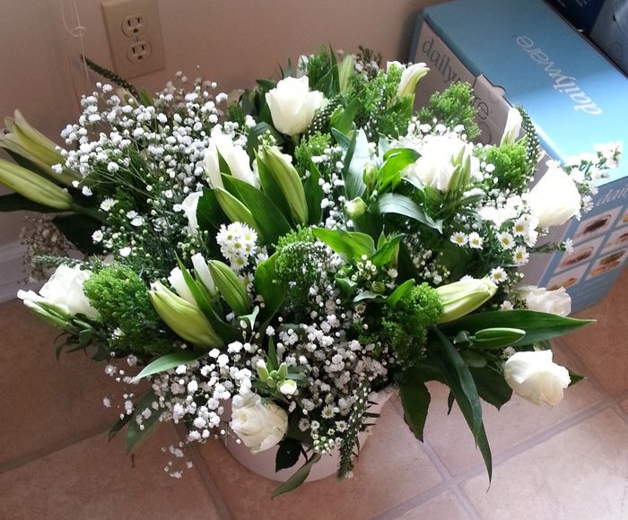 a bouquet of white flowers sitting on top of a counter next to a blue box